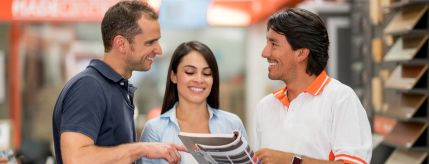 Man and woman talking to a sales person and looking at a brochure in at a flooring retailer